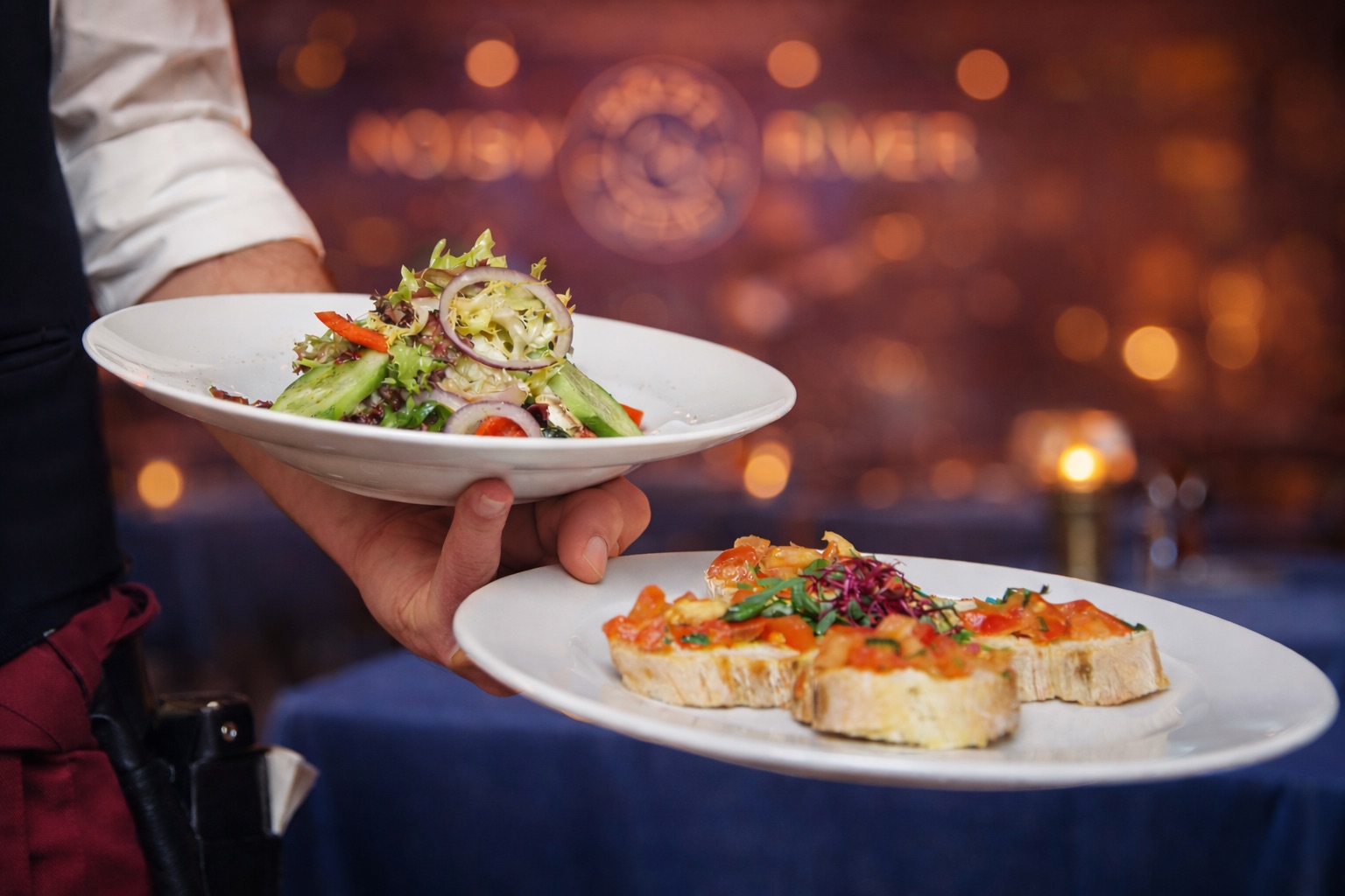 Официант подаёт блюда в ресторане Noisy River с живой музыкой и уютной вечерней атмосферой